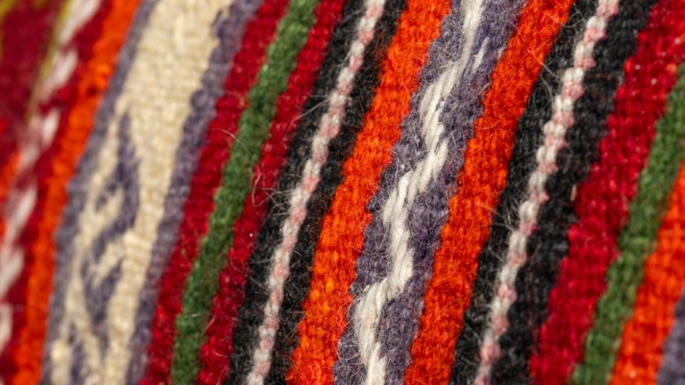 A Kashmiri artisan weaving a traditional hand-knotted carpet on a wooden loom